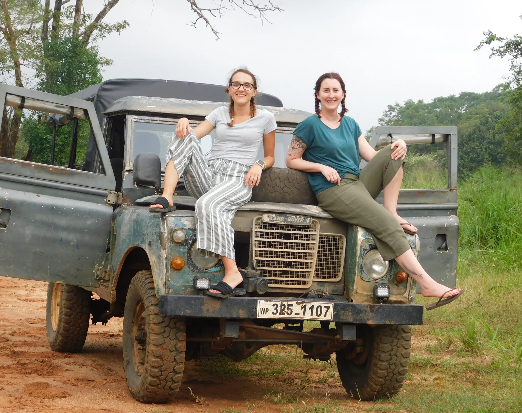 Two volunteers sitting on the bonnet of a field Land Rover