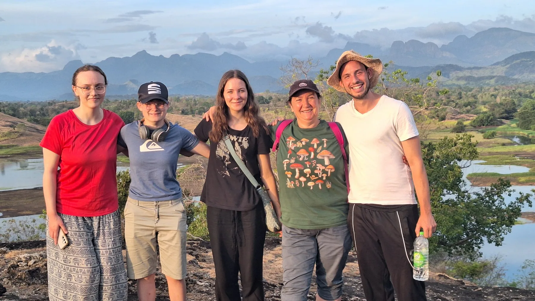 A group of volunteers smiling at a lakeside viewpoint