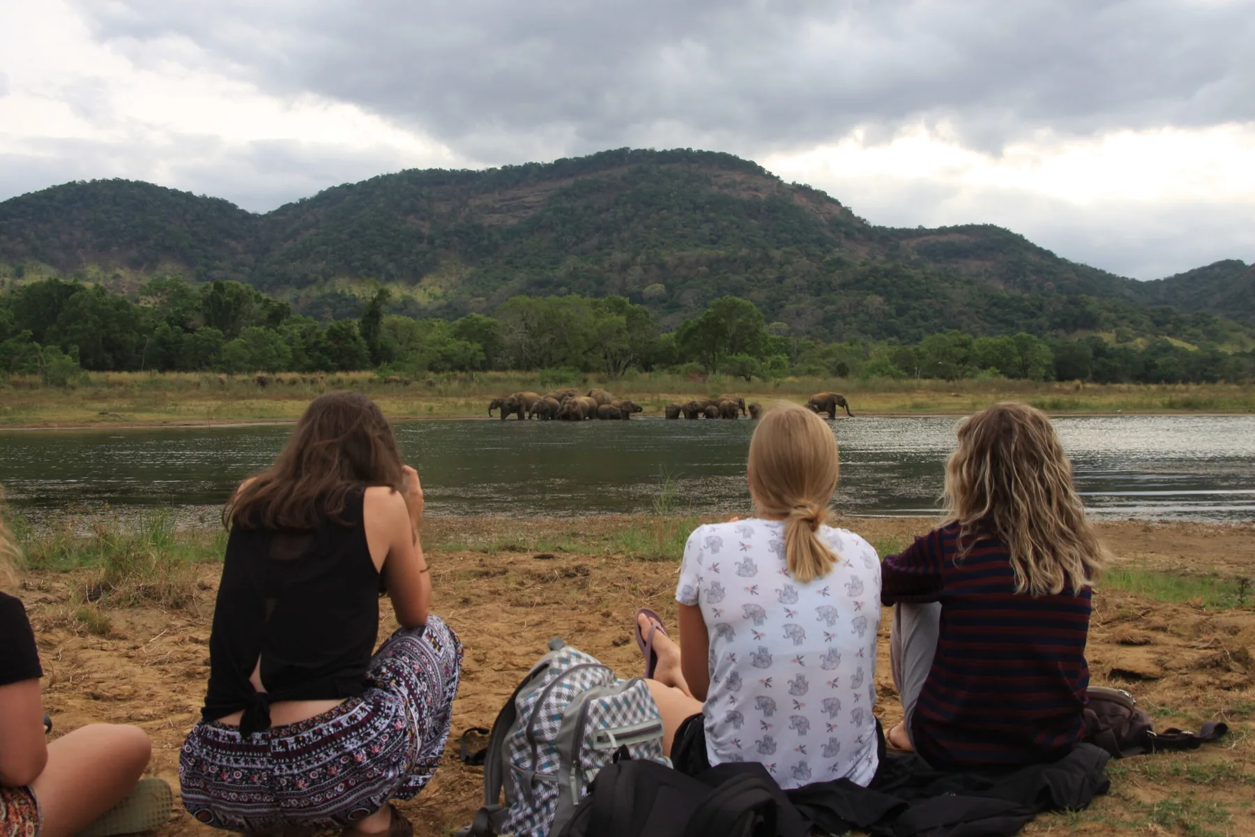 Volunteers resting on a lakeshore below the hills